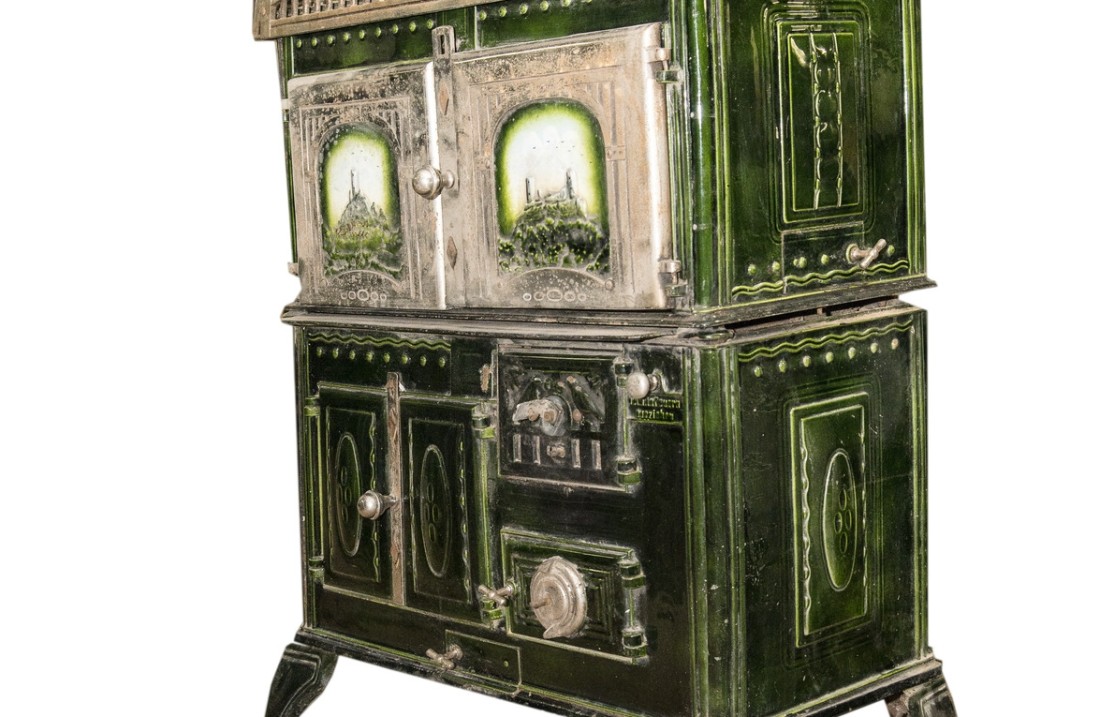 Economy cooker with a cast-iron hob that has two burners. The walls, doors and flaps are enameled green. The door through which the fuel is filled is located on the top right of the front panel. This firebox door has vents and is decorated with two birds. Bottom right is the ash door. Both door flaps have devices for air regulation in the fire or ash chamber. At the top right of the firebox is a knob that says 