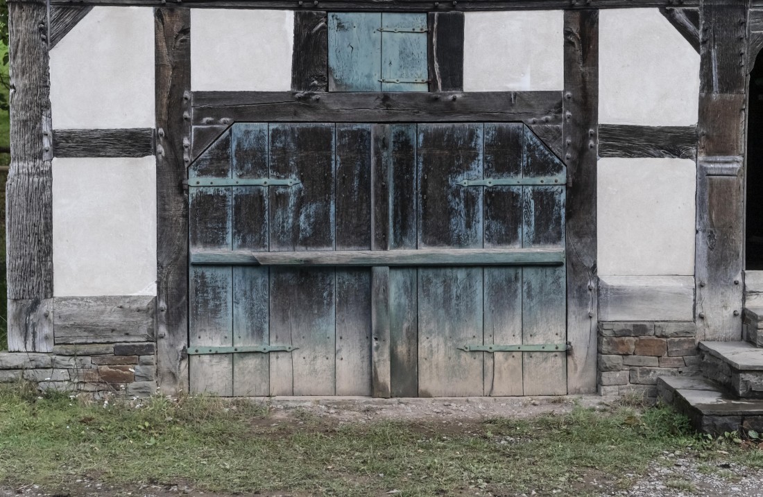 Holztor mit grün-blau schimmernder Grundtierung in einem Fachwerkhaus