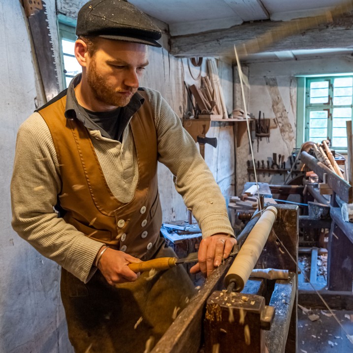 Mann arbeitet mit Feile an einem Holzstück