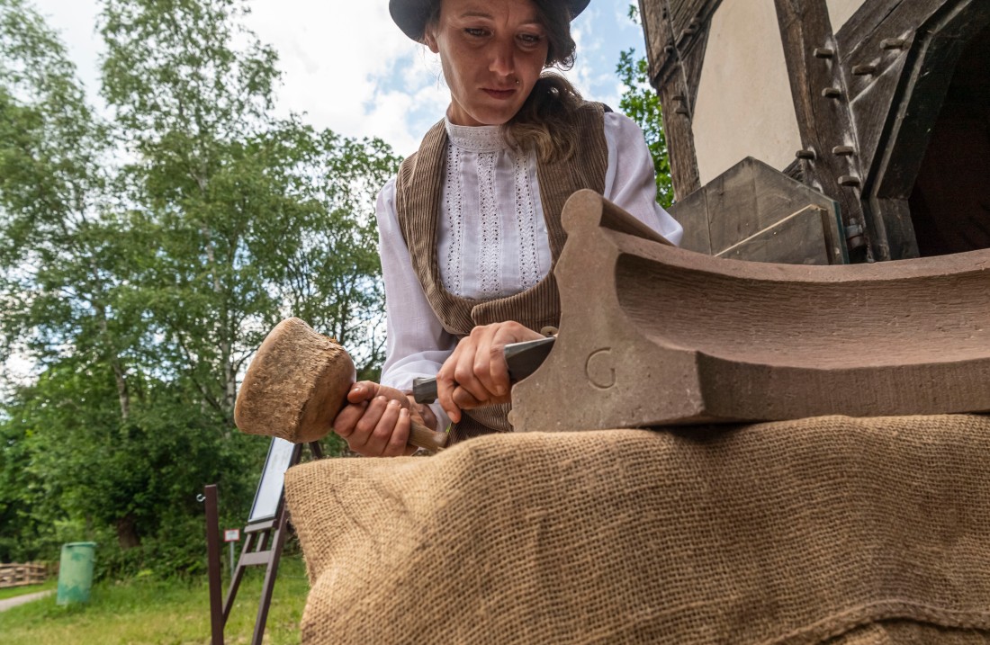 Woman works a stone with a hammer and chisel