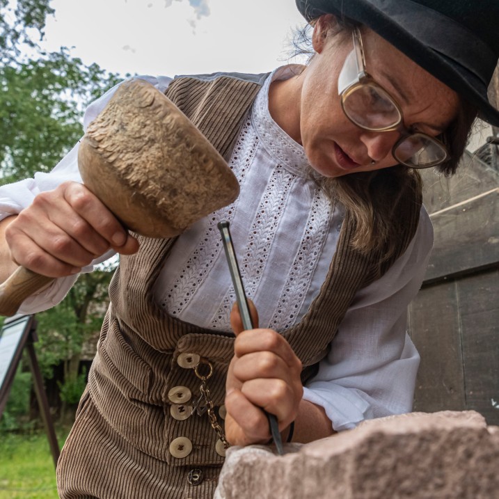 Eine Frau schlägt mit einem Hammer auf einen Meißel