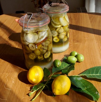 Nüsse auf einem Tisch, daneben Gläser mit eingelegten Beeren
