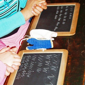 mit Kreide beschriebene Schiefertafeln, davor gefaltete Kinderhände