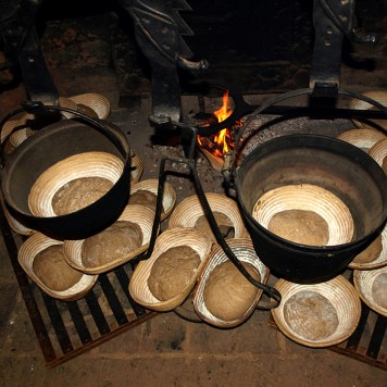 Feuer in einer Feuerstelle, davor Brote in Körben