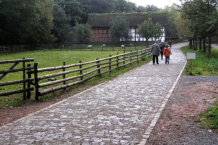Abbildung des Bodenbelags zeigt links ungeschnittenen und rechts geschnittenen Pflasterstein.