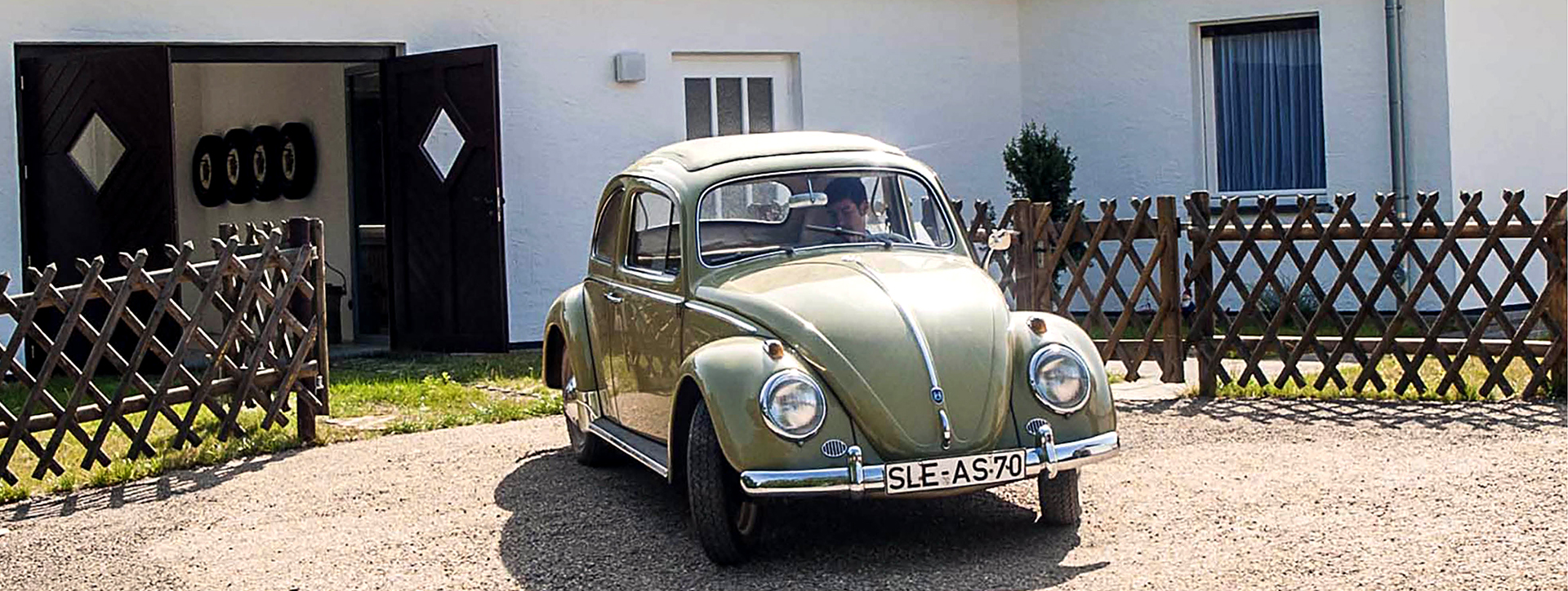 Alter VW-Käfer vor einem Bungalow