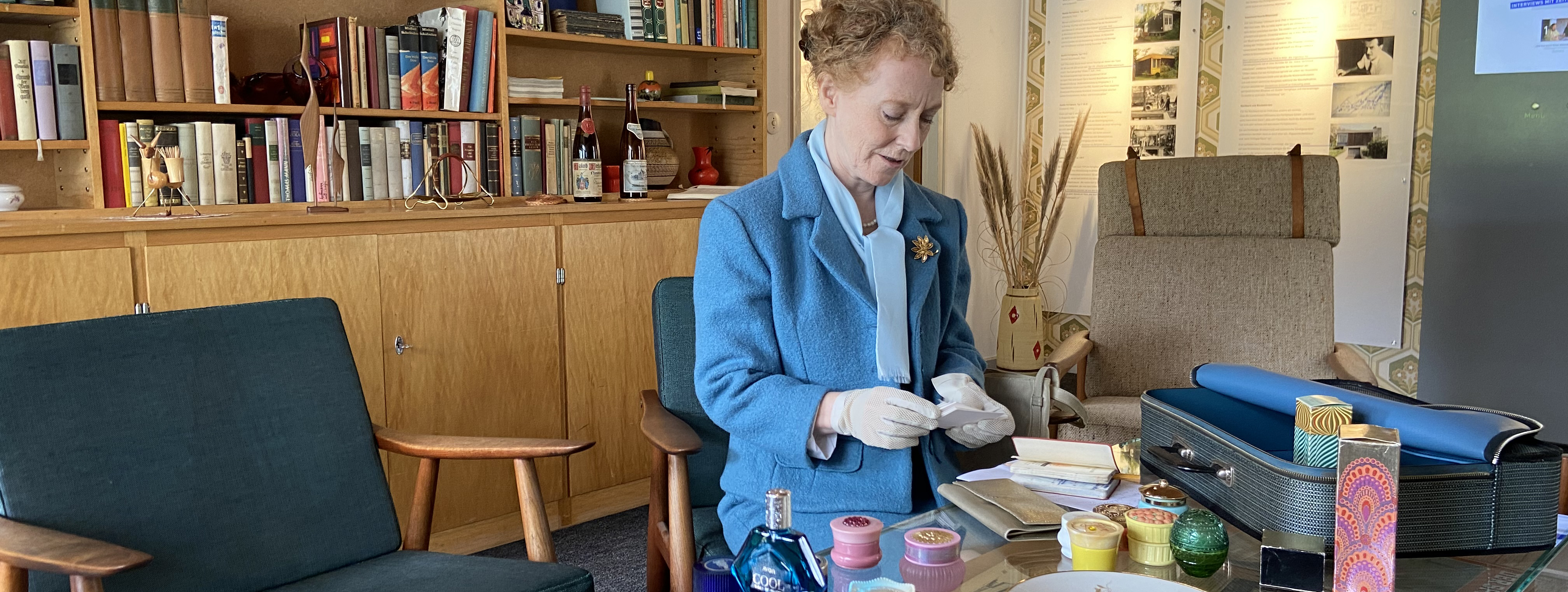 Woman in blue costume in front of a table with many bottles