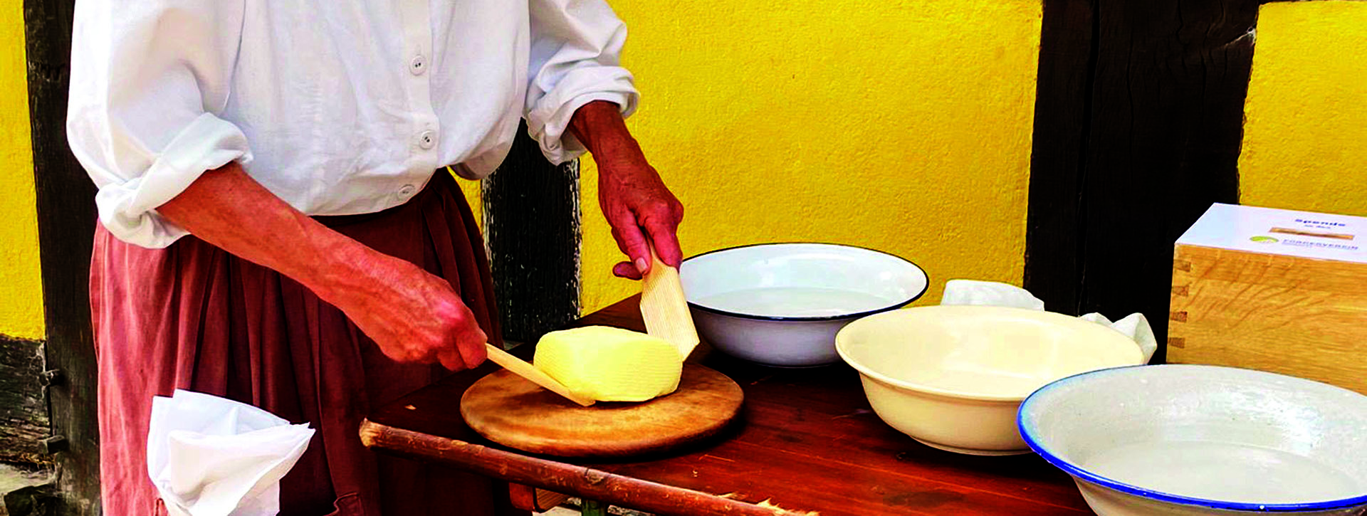 Frau in weißer Bluse und weißem Kopftuch bearbeitet Butter