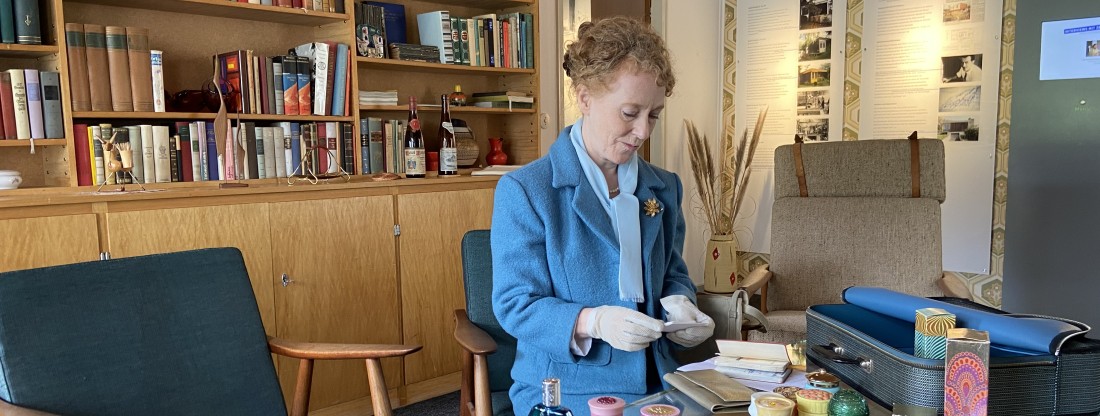 Frau mit Visitenkarten sitzt an einem Tisch voller Kosmektikprodukte