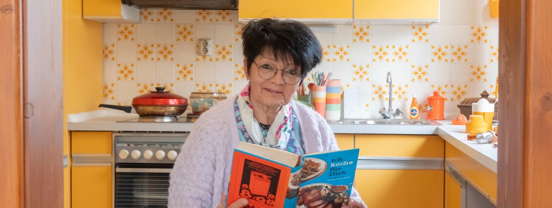 Frau in Kittelschürze liest in Kochbuch