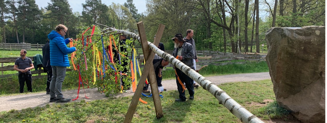Menschen beim Schmücken des Maibaums