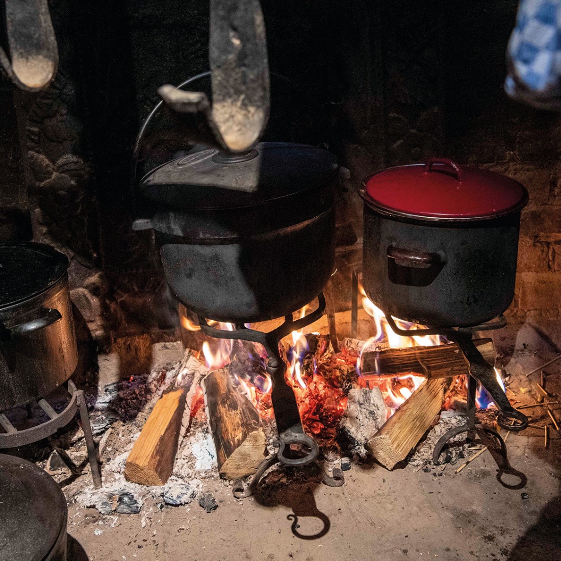 Cast-iron pots stand over a fire