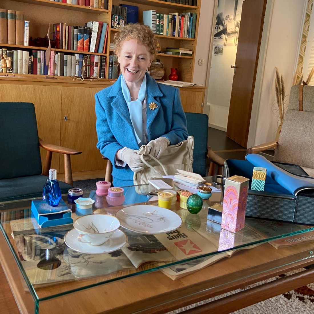 Woman in blue costume in front of a table with many bottles