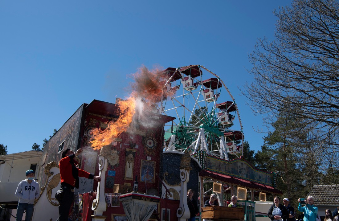 Feuerspucker in Aktion, im Hintergrund ein Riesenrad