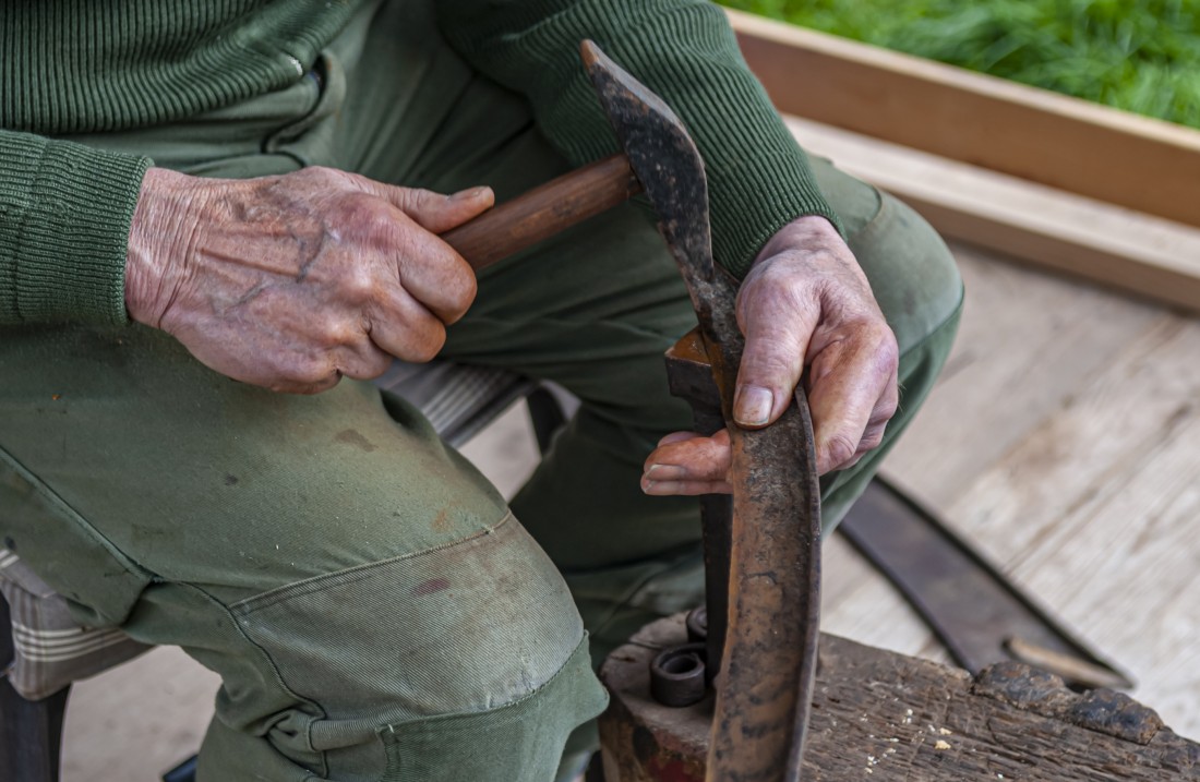 Mann repariert ein Metallstück mit einem Hammer