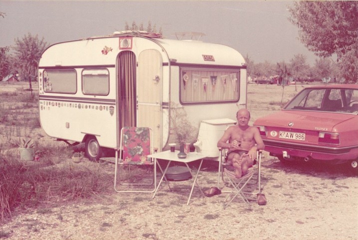 Mann vor Wohnwagen und Auto in den 1970er Jahren