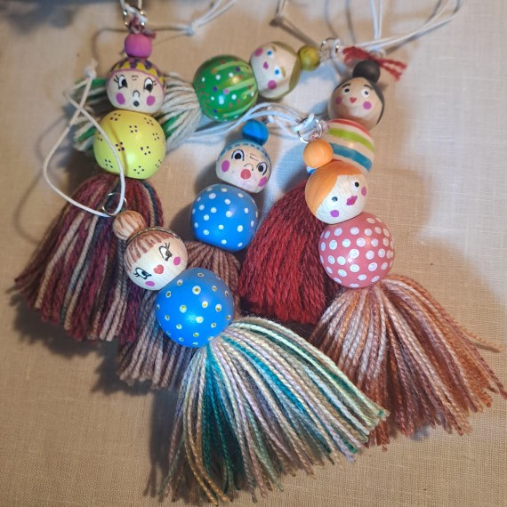 Kleine P&uuml;ppchen aus Holzkugeln und Wolle auf einem Haufen