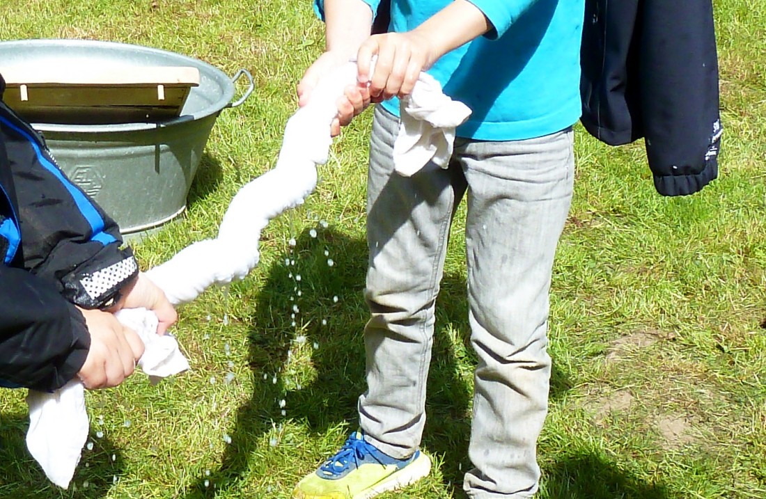 Kinder wringen ein nasses weißes Tuch aus