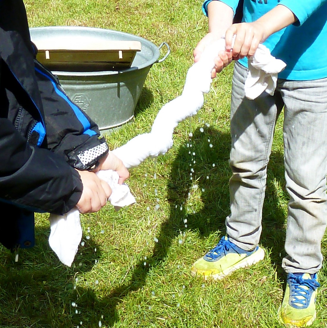 Children wring out a wet white cloth